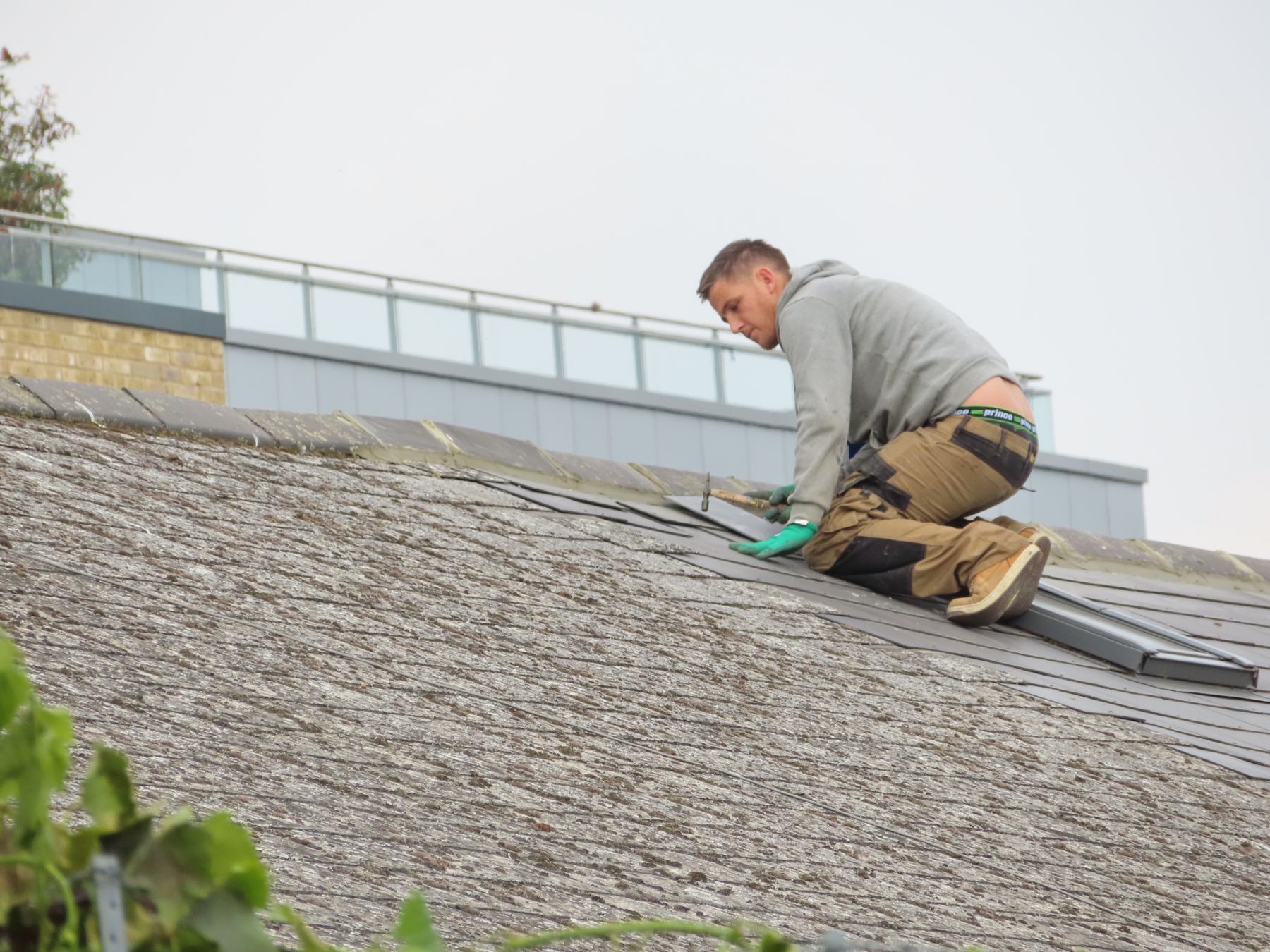 Roofer working on a weathered gray shingle roof